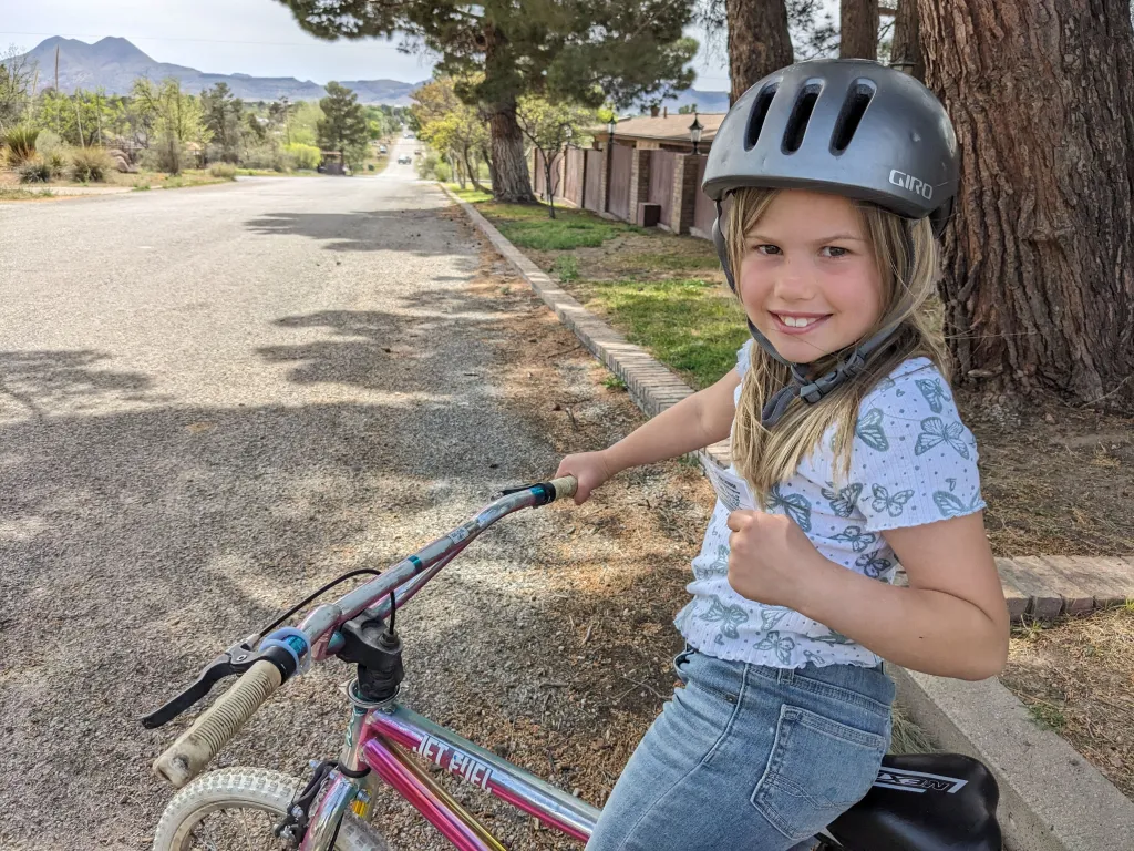 Rosy smiles while sitting on her bicycle and wearing a helmet.