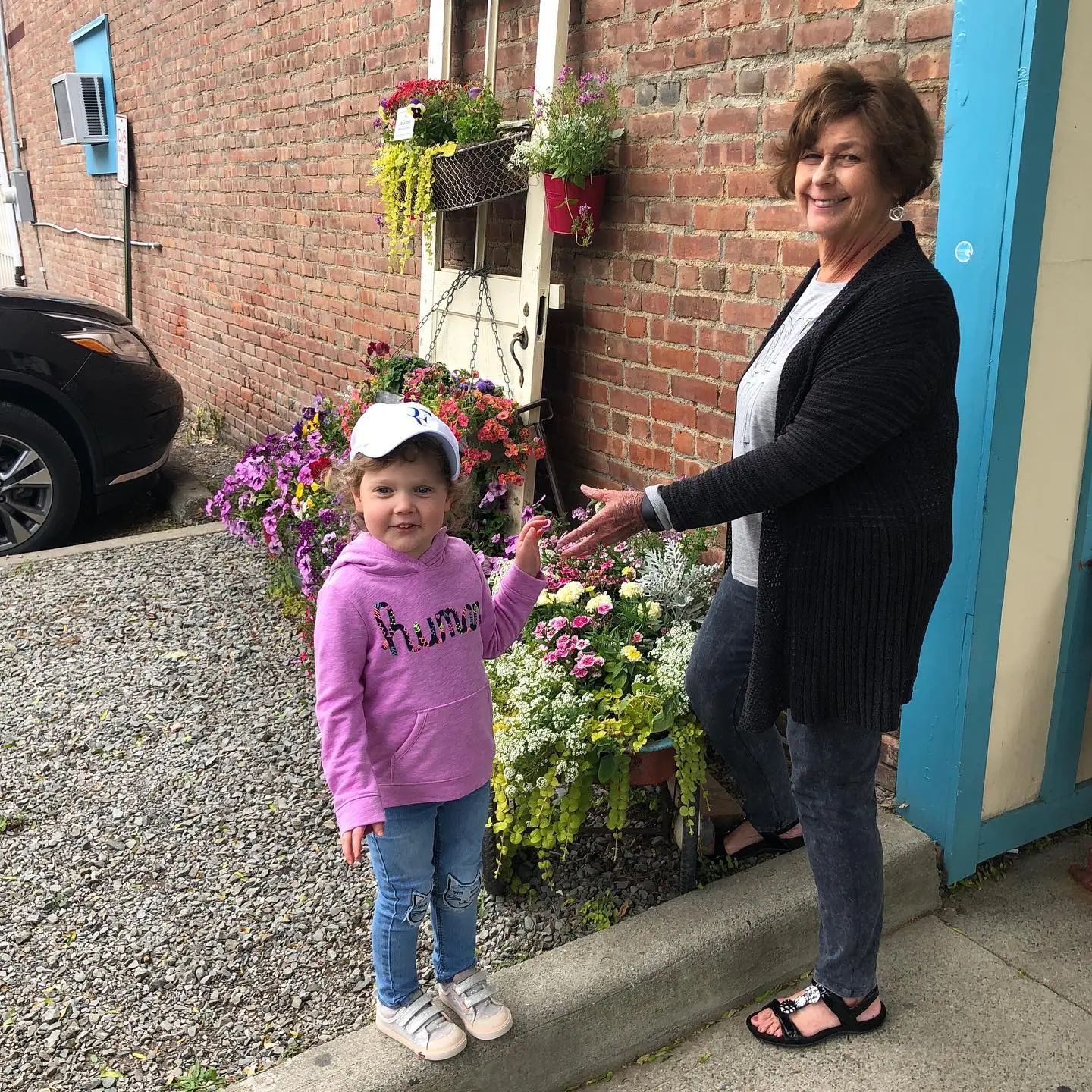 A young girl and her grandmother Nancy Guthrie stand among flowers.