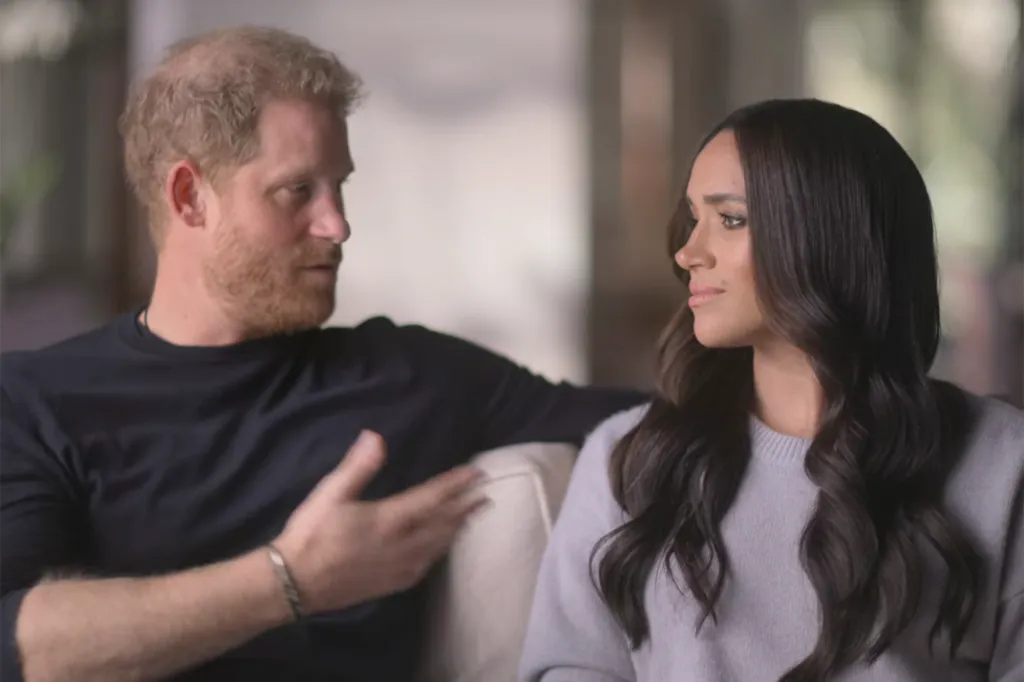 Prince Harry and Meghan Markle sitting on a couch, looking at each other.