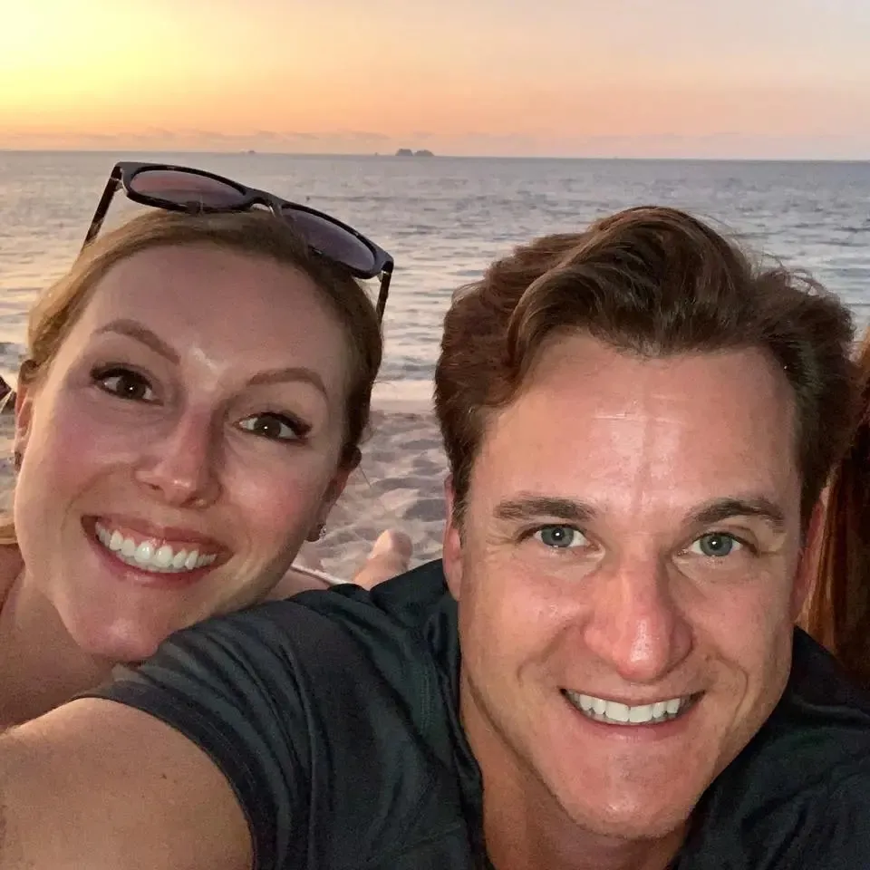 Gerhardt Konig and Arielle on a beach with the ocean behind them.