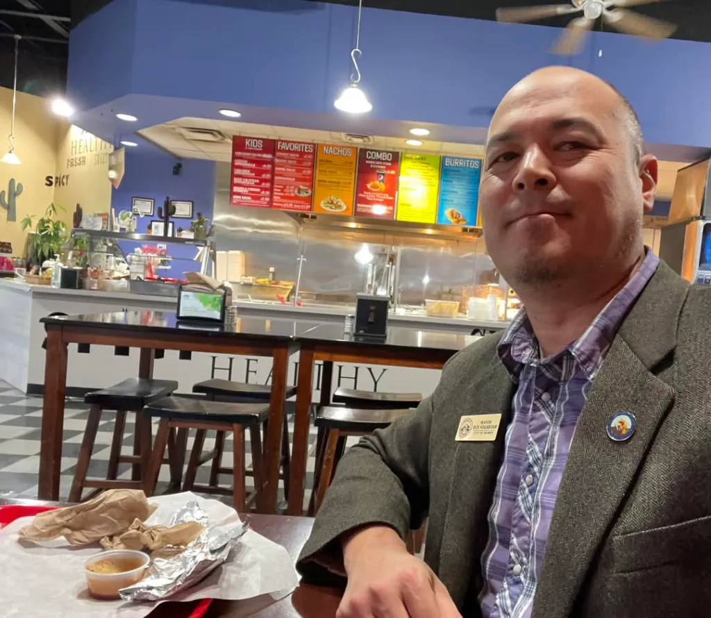 Mayor Hogaboam at a restaurant with a food menu in the background.