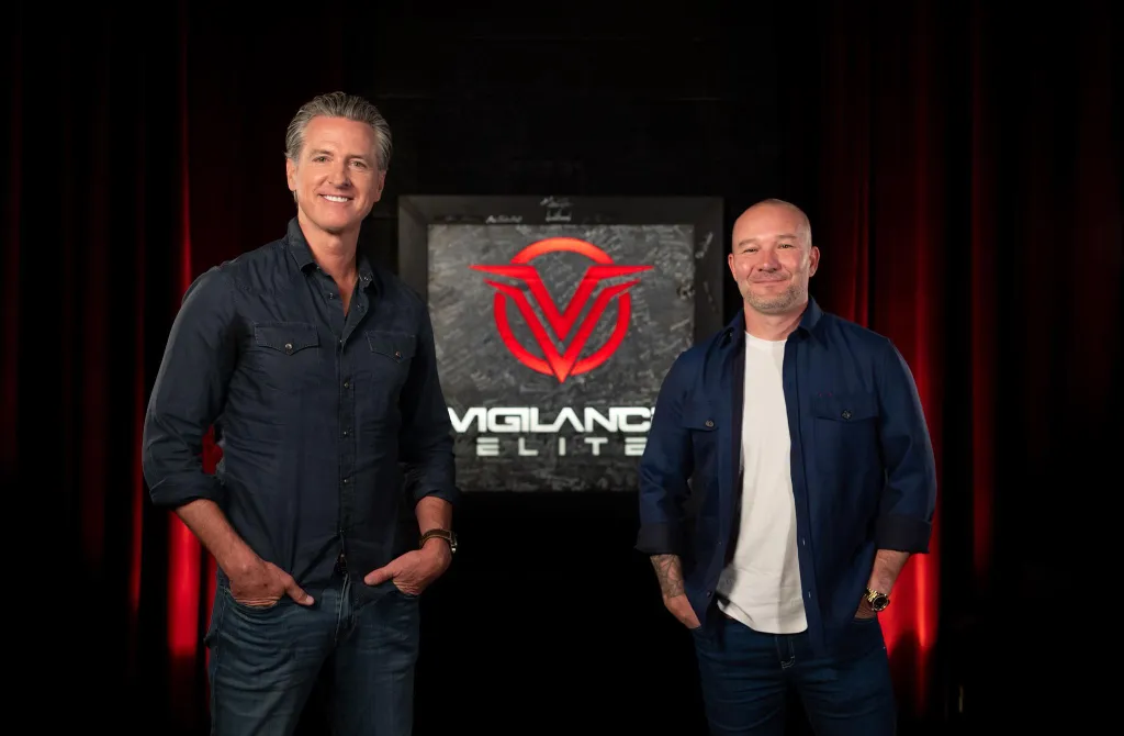 Gavin Newsom and Shawn Ryan stand smiling in front of a 