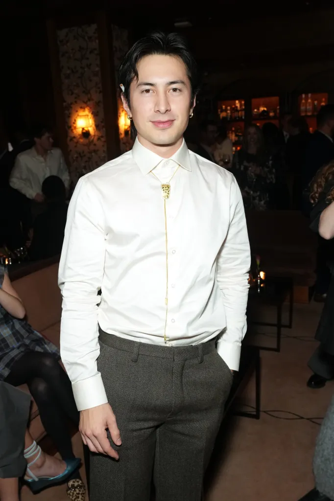 Hudson Williams wearing sunglasses and a brown trench coat.