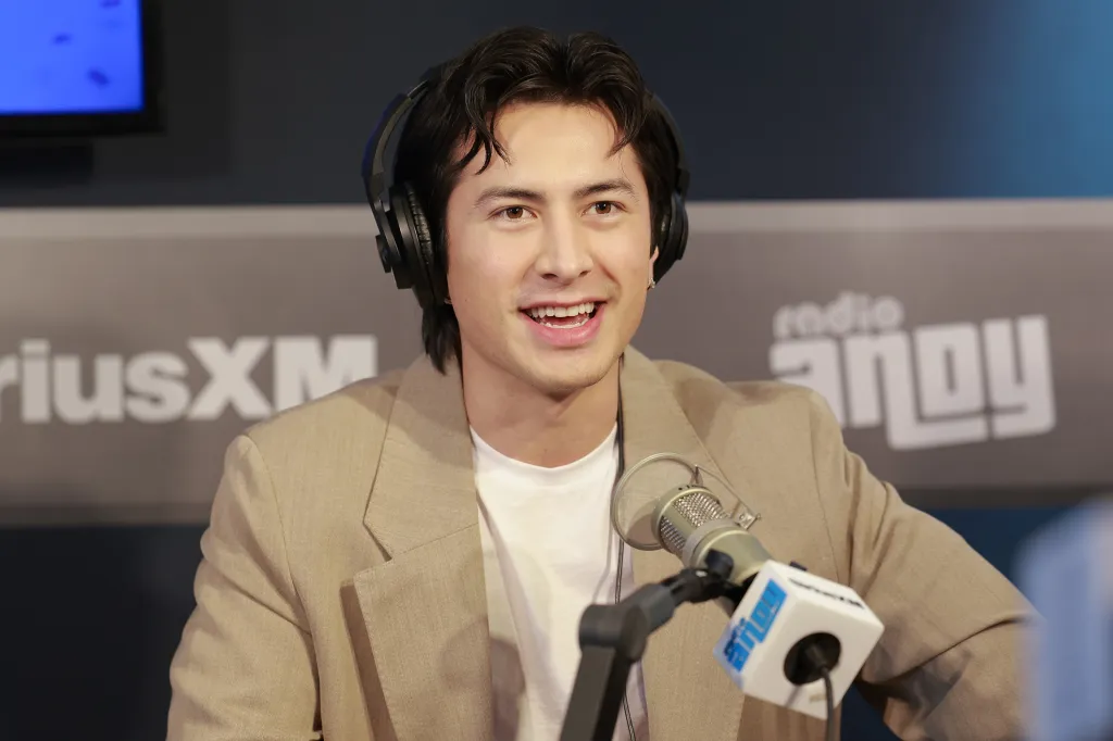 Hudson Williams smiling while wearing headphones and speaking into a microphone at SiriusXM Studios.