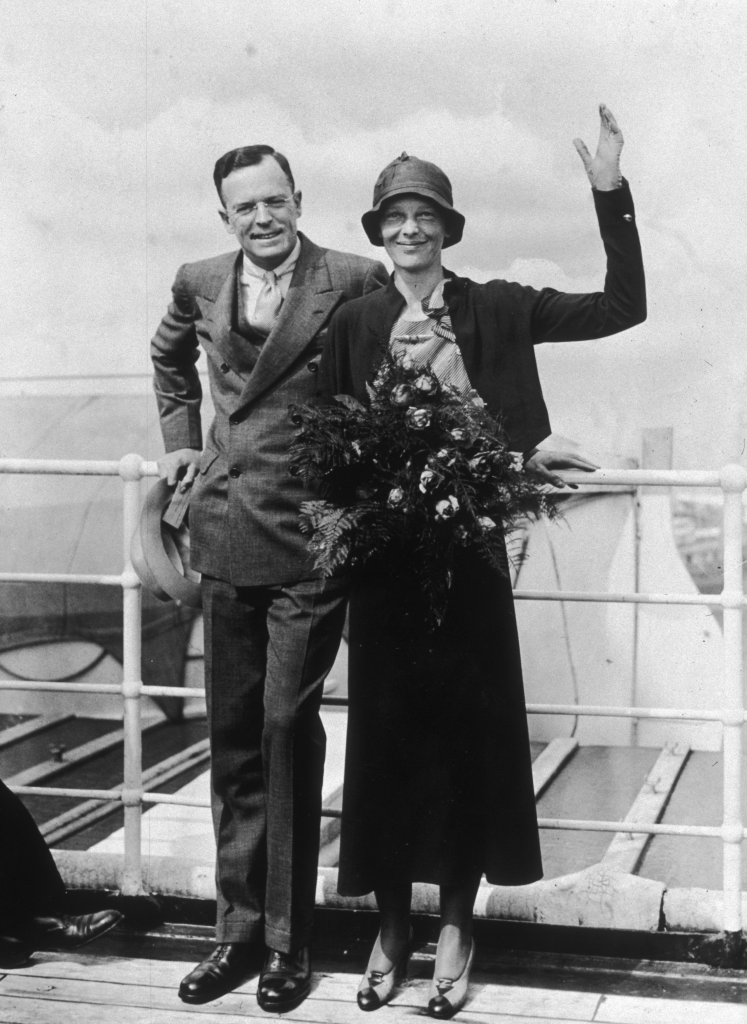 Amelia Earhart and George Palmer Putnam waving on a ship.