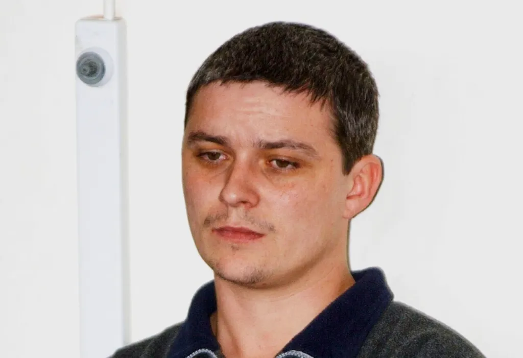 Ian Huntley looking down, wearing a dark blue polo shirt.