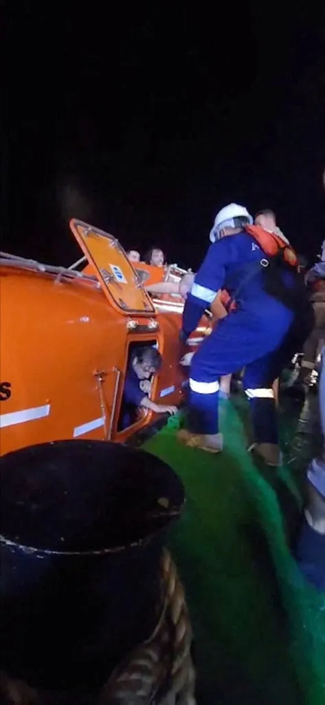 A rescuer guides a man out of a lifeboat, after Iran attacked two fuel tankers in Iraqi waters setting them ablaze.