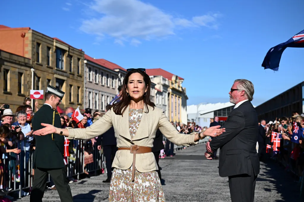 Queen Mary of Denmark with arms outstretched in front of a crowd.