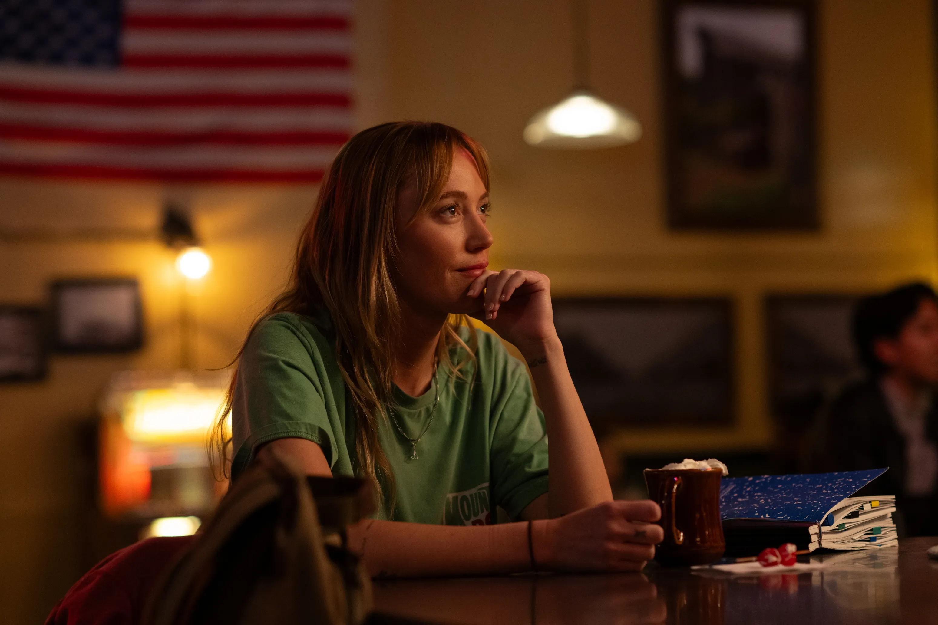 Maika Monroe as Kenna, sitting at a bar with a drink.