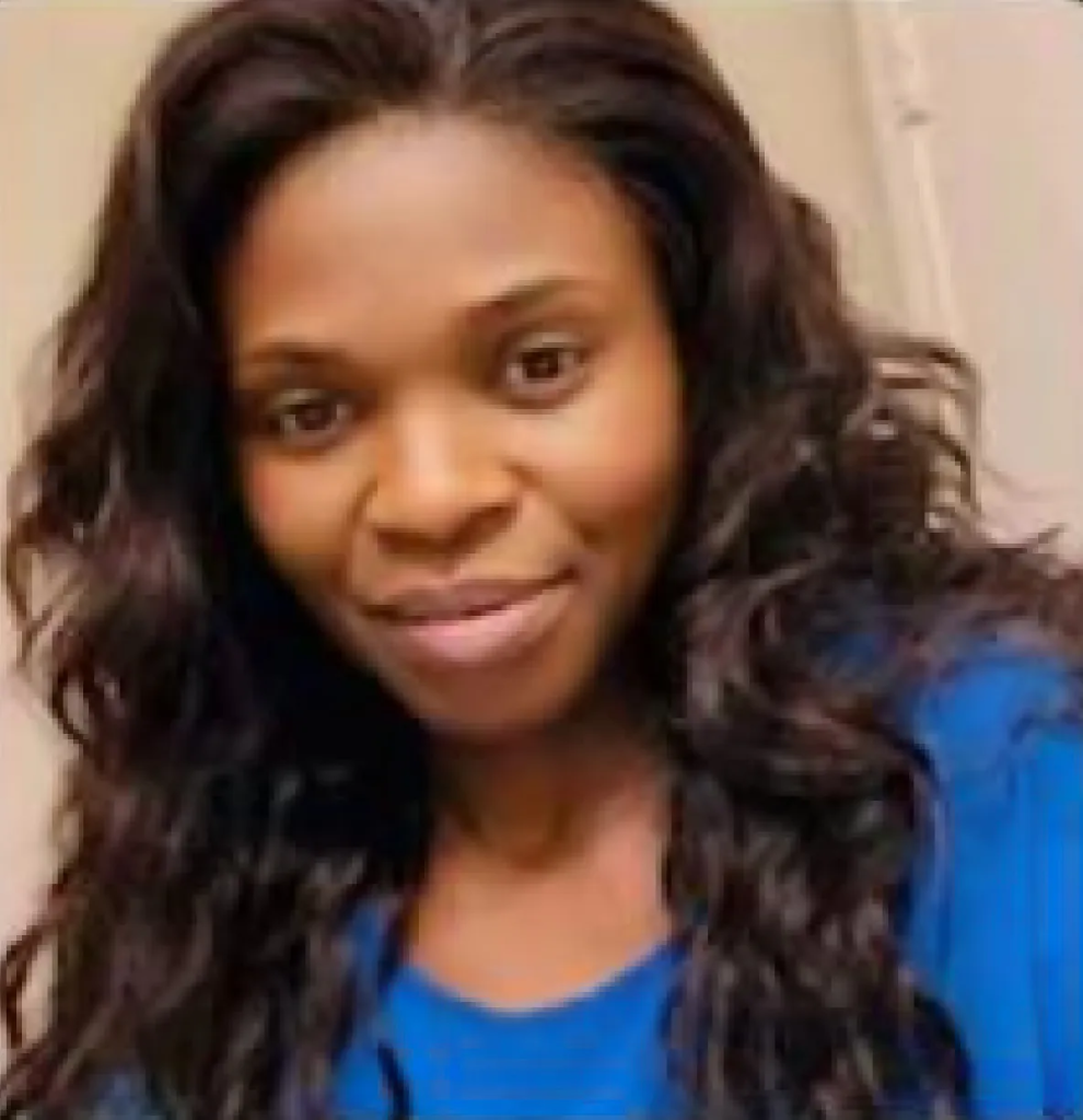 A woman with long, dark, wavy hair and a blue shirt smiles at the camera.