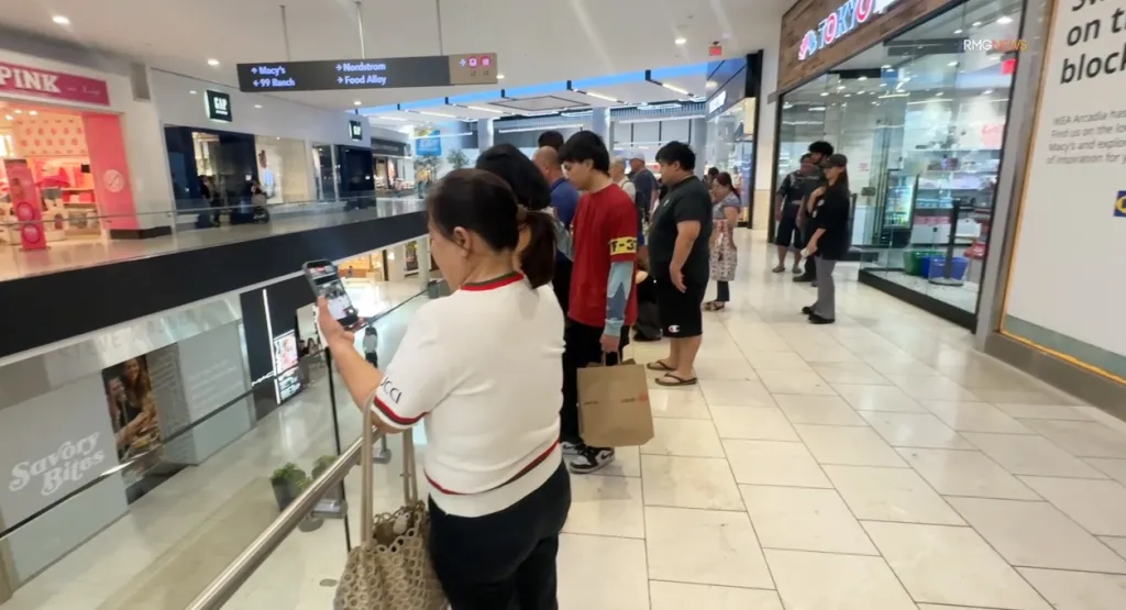 People gathered in a mall, with one person filming on a phone, possibly during a swatting incident.