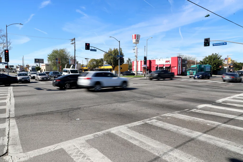 A busy intersection in Los Angeles, California, with cars, traffic lights, and a KFC restaurant.