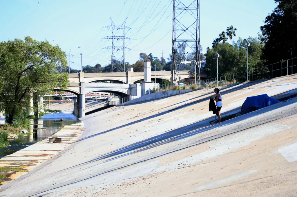 A homeless woman washes clothes in the LA River.