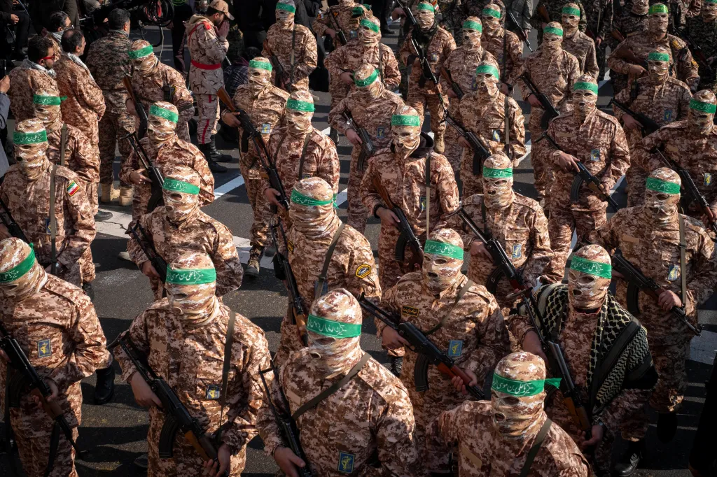 Armed personnel of the Islamic Revolutionary Guard Corps in camouflage and masks holding rifles at a military rally.