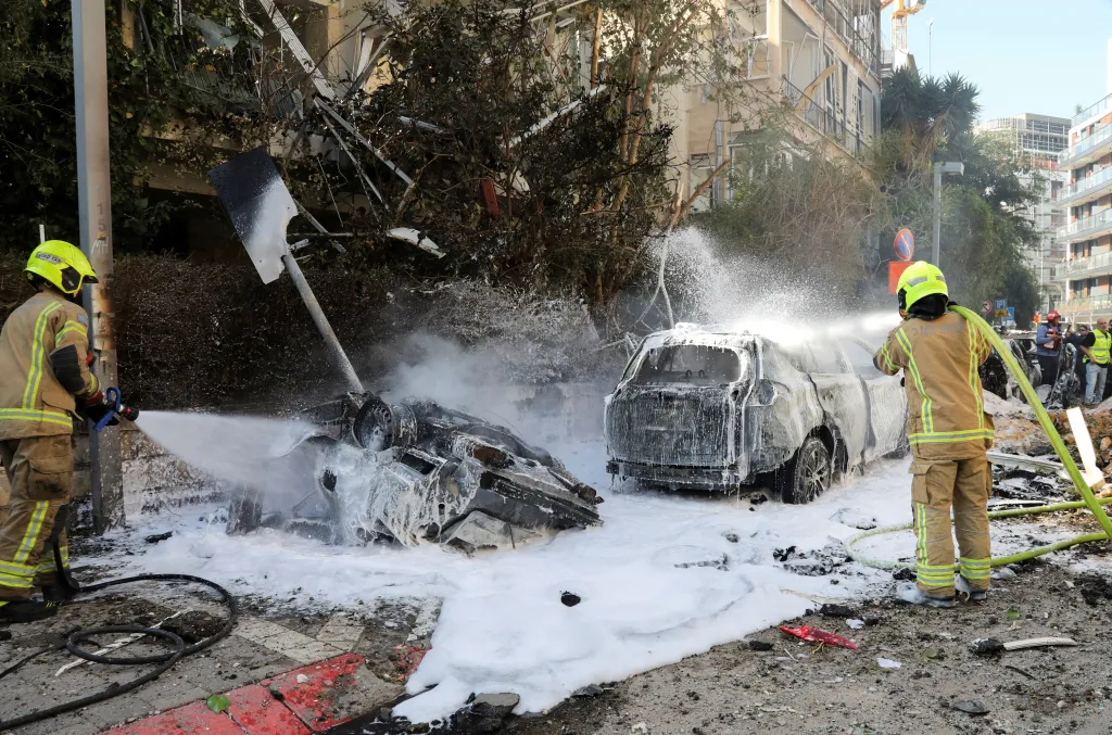 Firefighters extinguishing a fire from burned cars with foam following missile strikes in Tel Aviv.