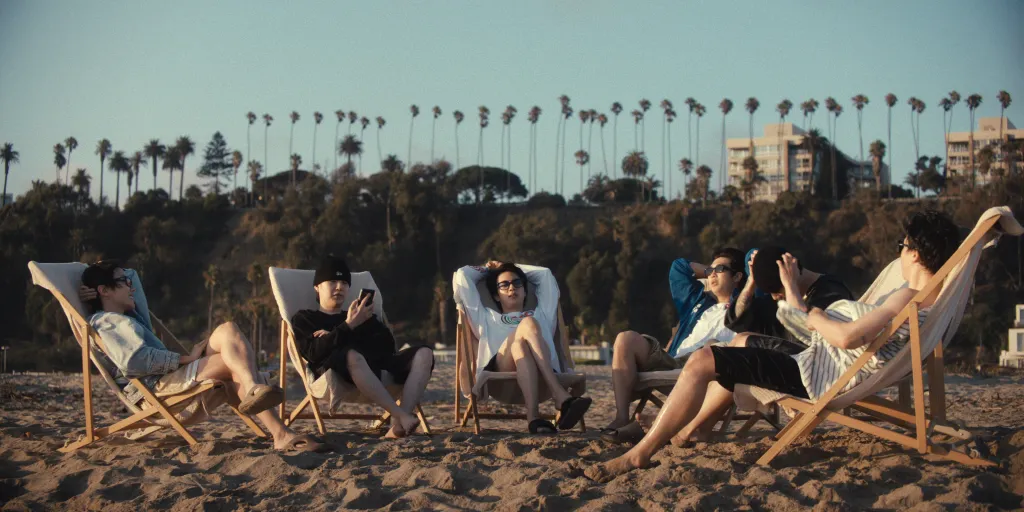 BTS members j-hope, Suga, Jin, and RM relaxing in beach chairs.