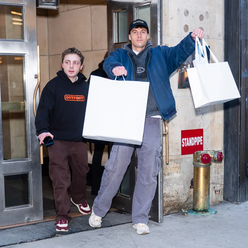 Jake Shane and Rob Rausch carrying shopping bags in New York City.