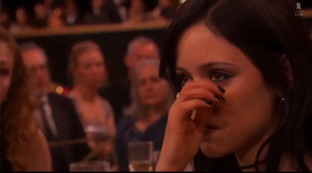 Jenna Ortega wiping tears from her eyes during a tribute to Catherine O'Hara.