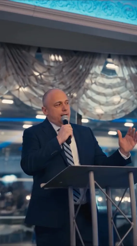 Jeremy Scheublin speaking at a podium while receiving the Man of the Year award.