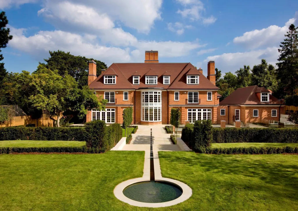 Jersey House in North London, a large brick home with a red roof, dormer windows, and a fountain in the front yard.