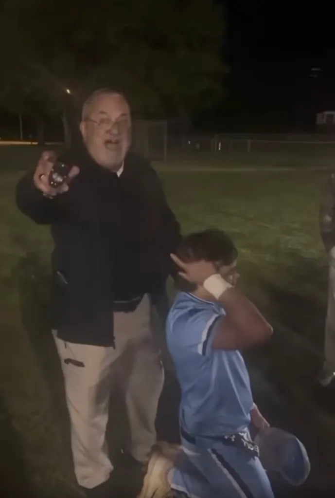 An officer from Pee Dee Academy holding a Taser and pointing it while standing over a boy who is covering his head.