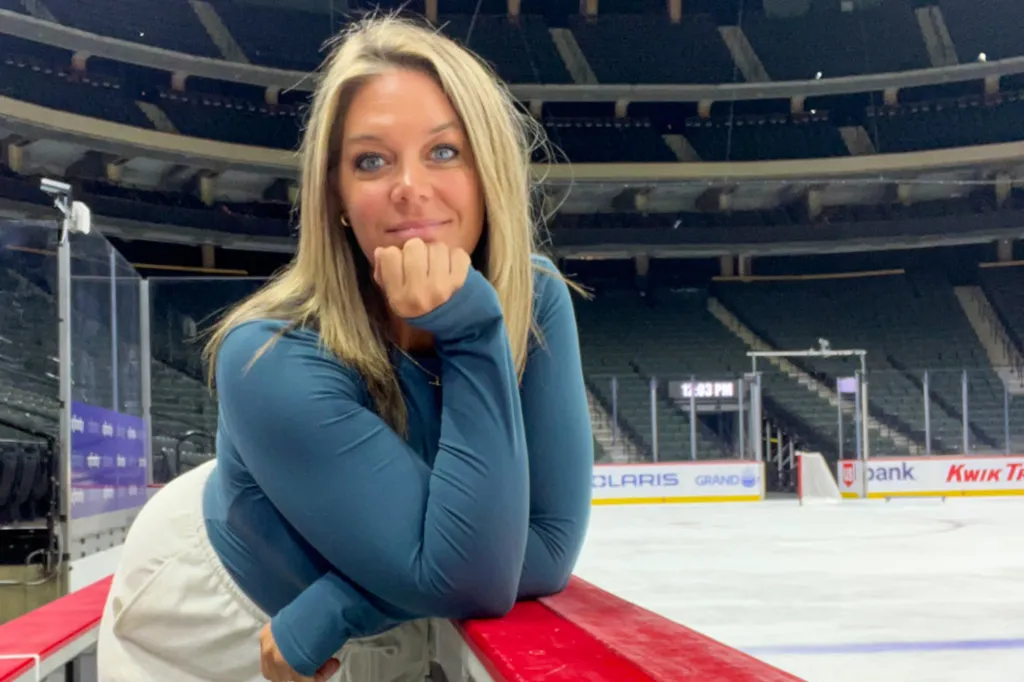 Jessi Pierce leaning on the hockey rink boards.