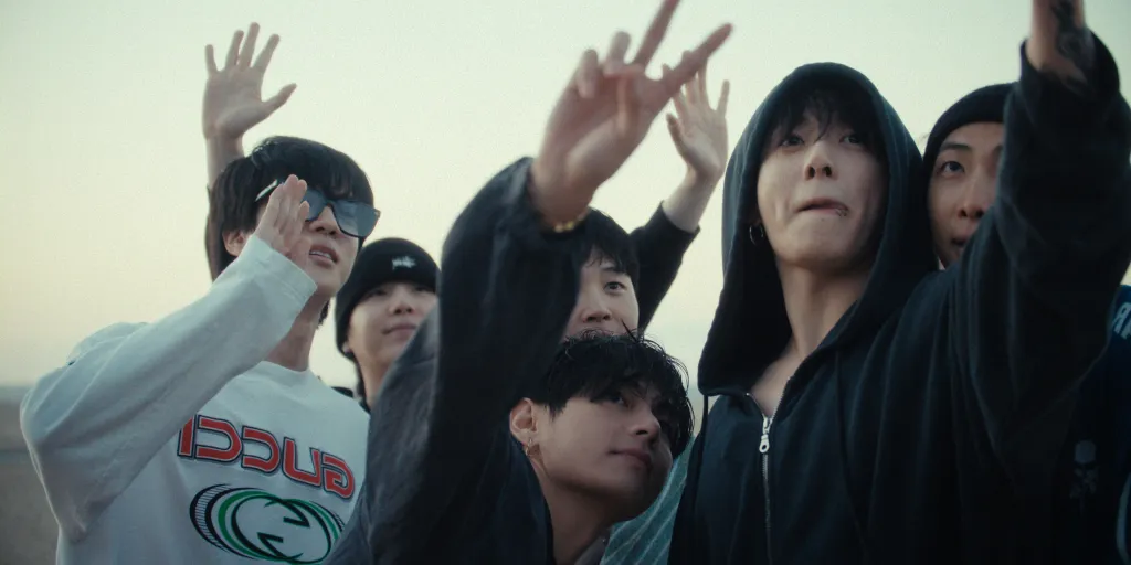 BTS members Jin, Suga, Jimin, V, Jung Kook, and RM with their hands raised.