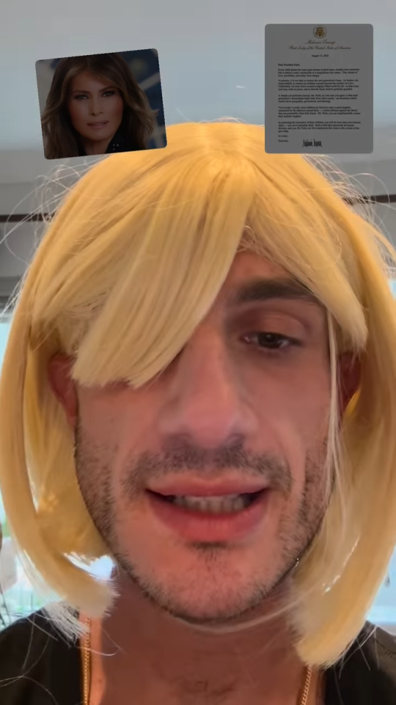 Jack Schlossberg mocking Melania Trump, wearing a blonde wig and with images of Trump and her letter to Putin in the background.