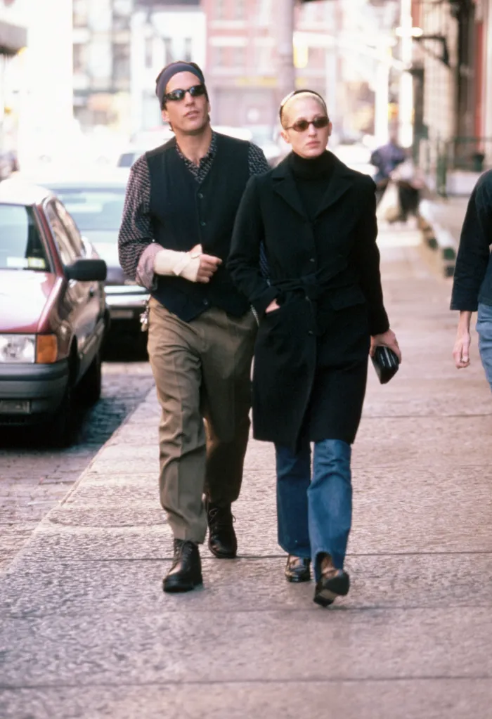 John F. Kennedy Jr. and Carolyn Bessette-Kennedy walking on a city street.