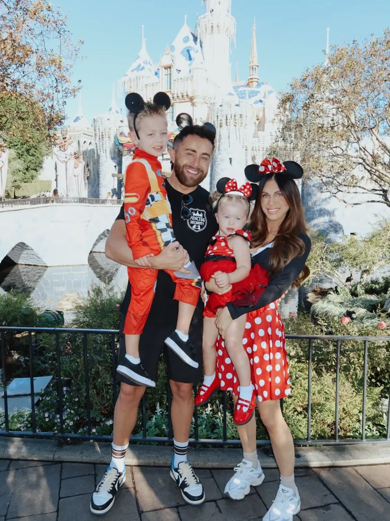 Jordan and Jessi Ngatikaura with their two children in front of a Disney castle.