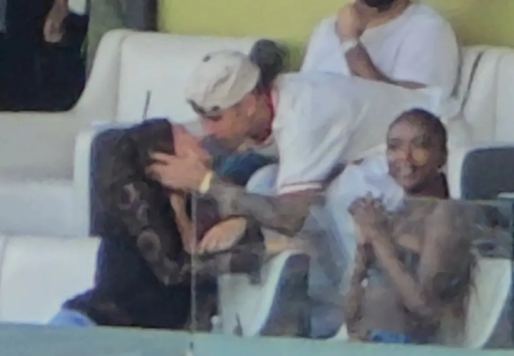 Justin and Hailey Bieber kissing in a VIP box at a celebrity flag football game.