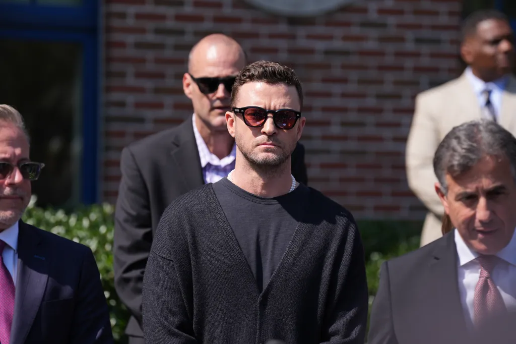 Justin Timberlake wearing sunglasses and a black cardigan appears in court with his lawyer for a DWI hearing.