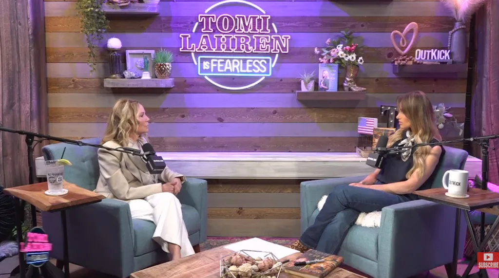 Two women, Kathie Lee Gifford and Tomi Lahren, sitting in armchairs across from each other in a podcast studio with a neon sign that reads 