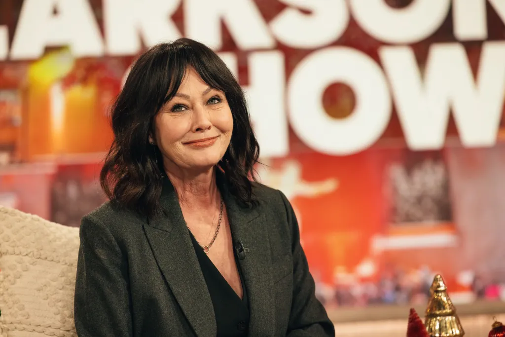 Shannen Doherty smiling while sitting in a chair on The Kelly Clarkson Show.