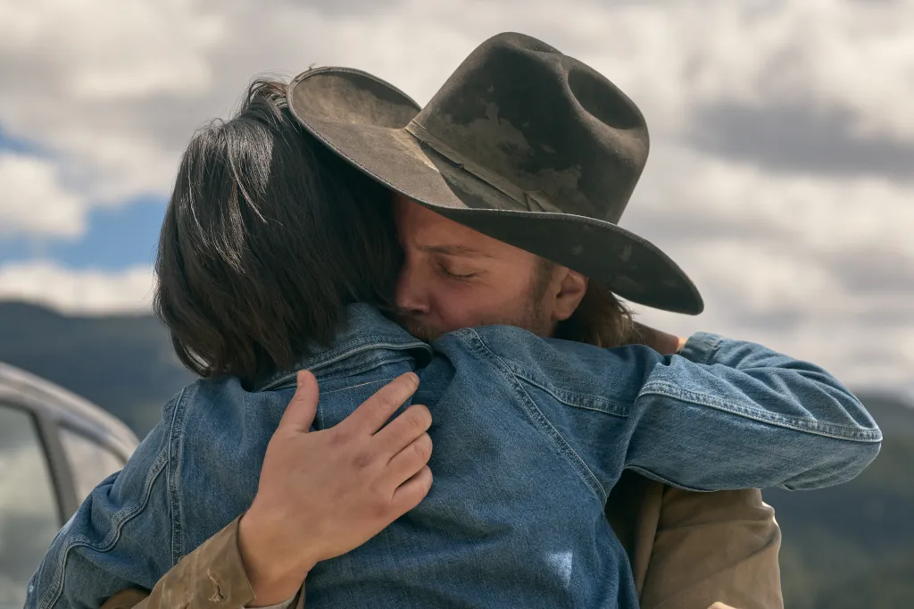 Kelsey Asbille as Monica Long and Luke Grimes as Kayce Dutton embracing.
