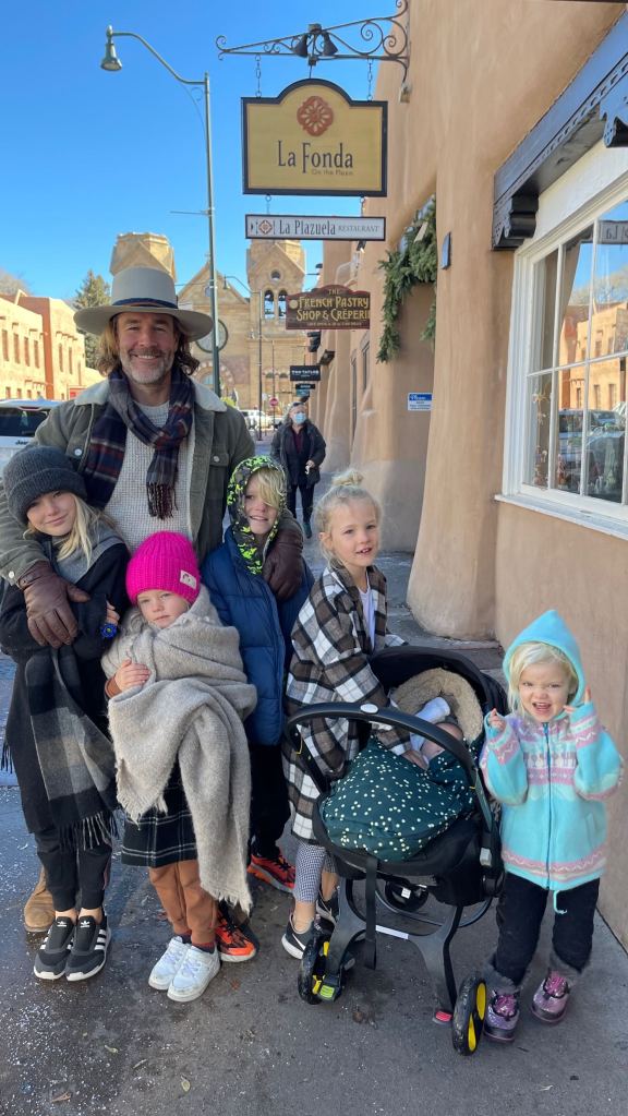 James Van Der Beek posing with his wife and kids on the street outside a restaurant called 
