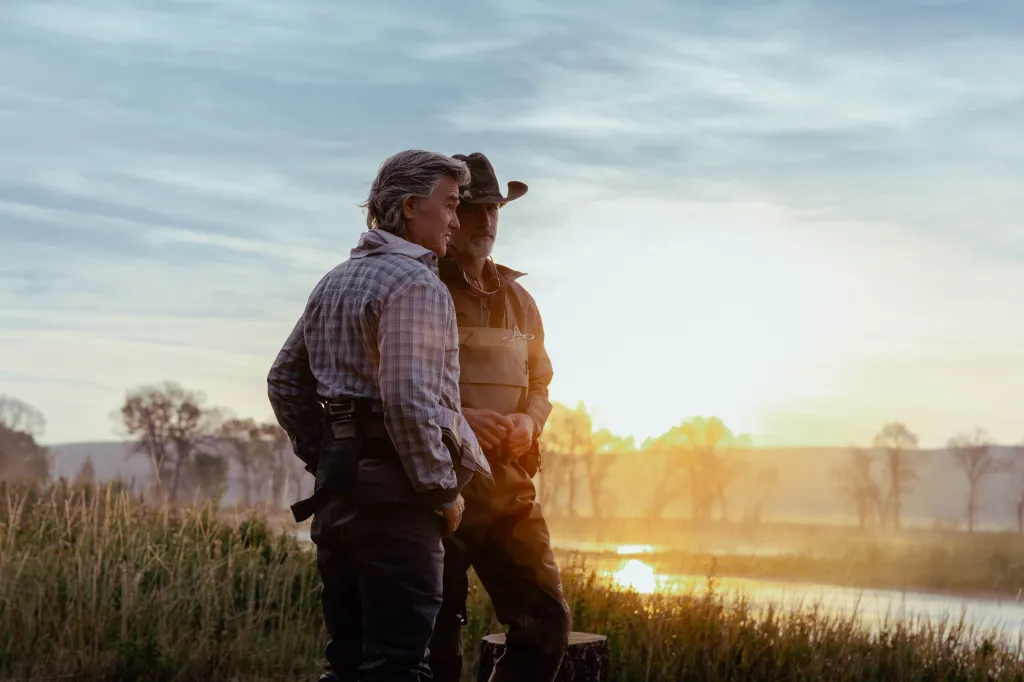 Kurt Russell as Preston Clyburn and Matthew Fox as Paul Clyburn stand together in an outdoor setting at sunrise.