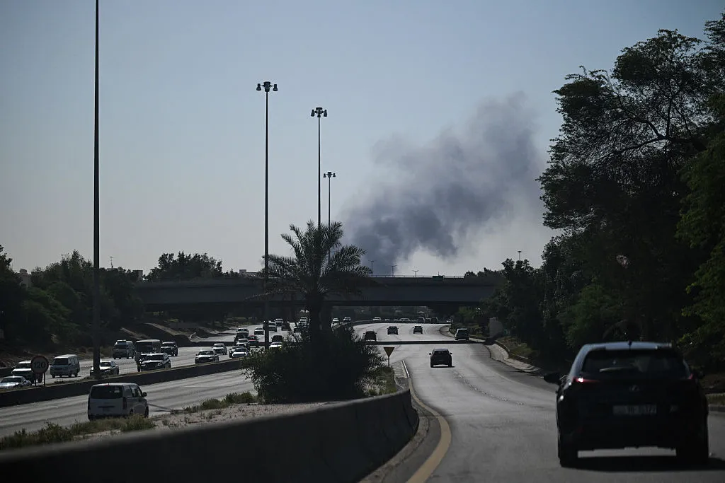 Motorists drive along a street as smoke rises from a reported Iranian strike in the area where the U.S. Embassy is located in Kuwait City on March 2, 2026. 