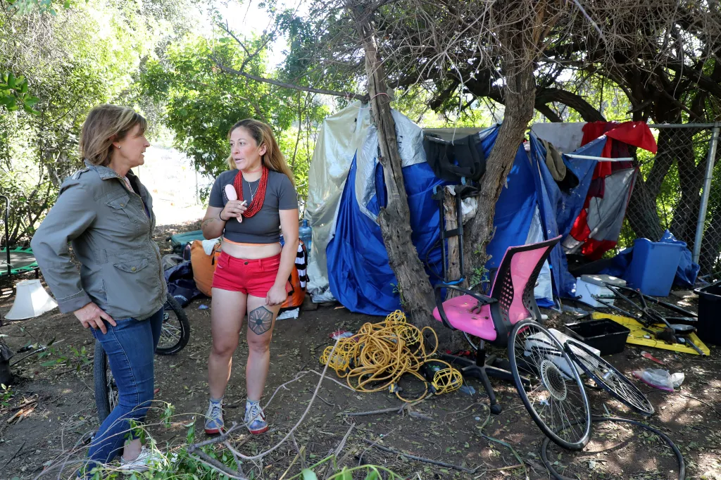 Homeless advocate Cameron Flanagan speaks with Kween beside Kween's shelter on the banks of the LA river.