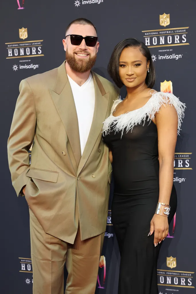 Travis Kelce in a tan suit and Kayla Nicole in a black dress with feather trim at the NFL Honors.