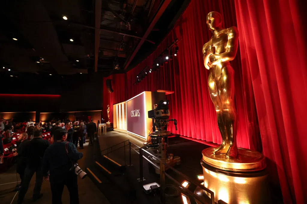 A large Oscar statue in front of a red curtain at the Samuel Goldwyn Theater.