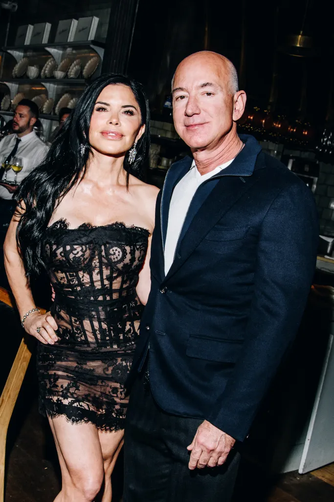 Lauren Sanchez in a black lace dress and Jeff Bezos in a dark blue jacket.