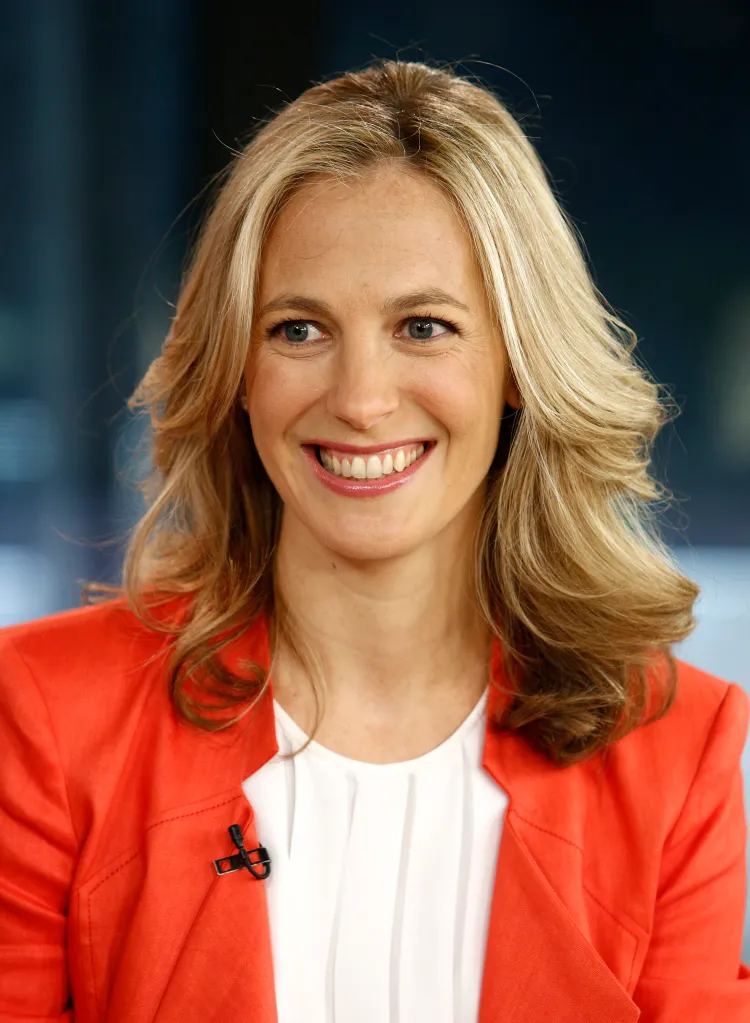 Headshot of Lauren Weisberger smiling, in an orange jacket and white top.
