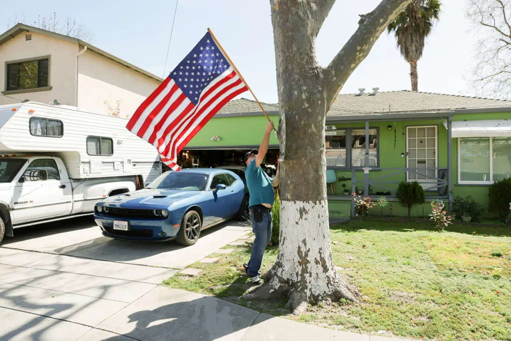 Lawrence Smith holds an American flag outside his home.