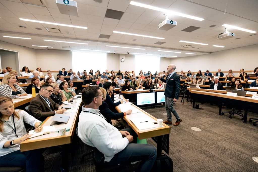 Arthur C. Brooks teaches an in-person class on the science of happiness to a large group of students in a lecture hall.