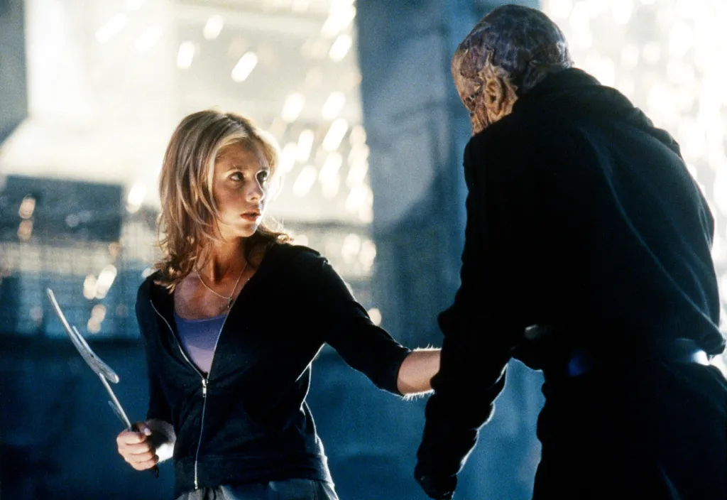 Sarah Michelle Gellar as Buffy holding a weapon while confronting a monster in 