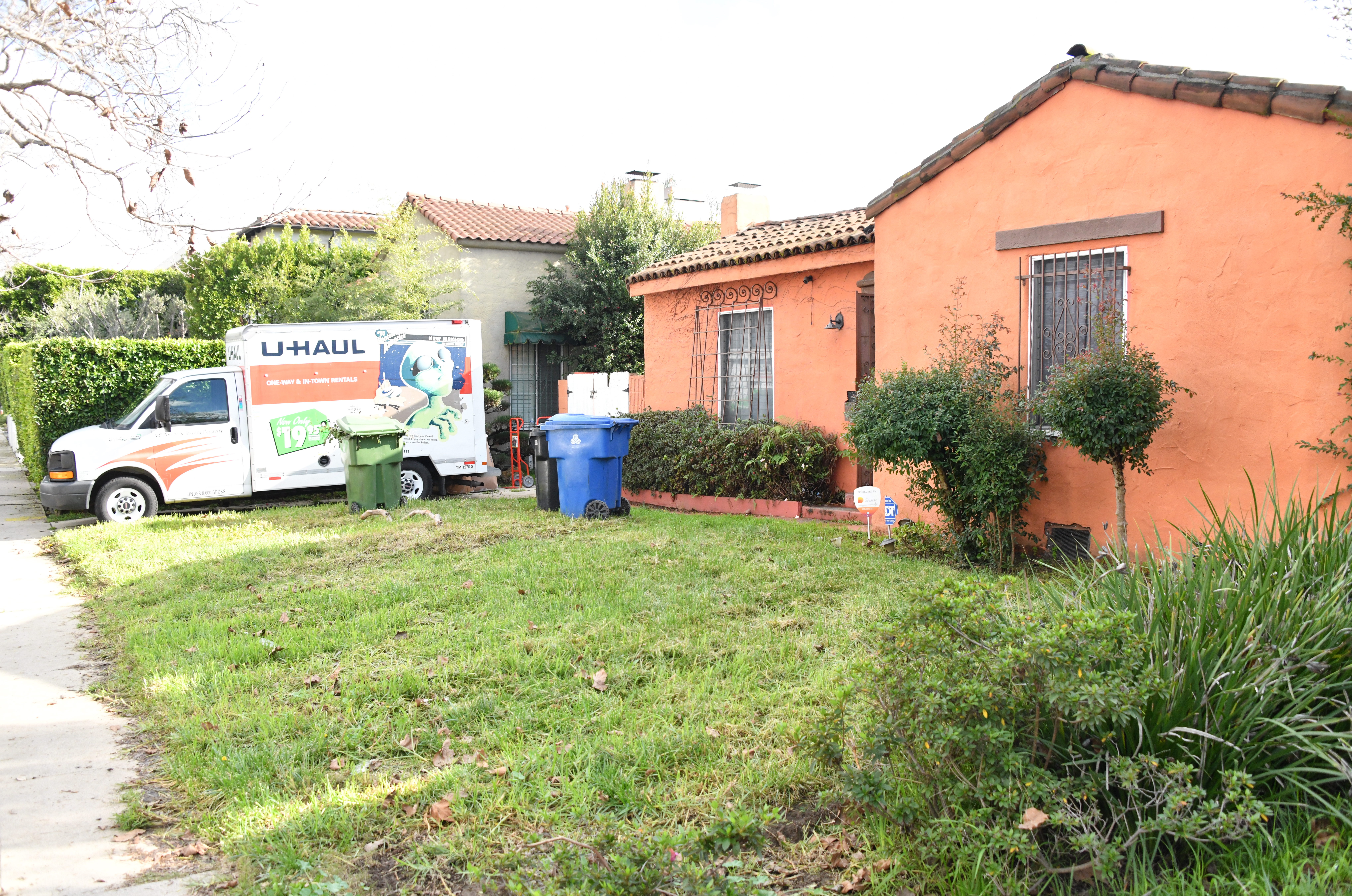 A Spanish-style bungalow with an orange exterior, with a U-Haul truck parked in the driveway.