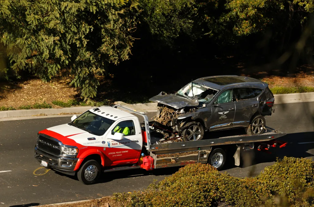A damaged dark gray SUV is being towed away on a flatbed tow truck.