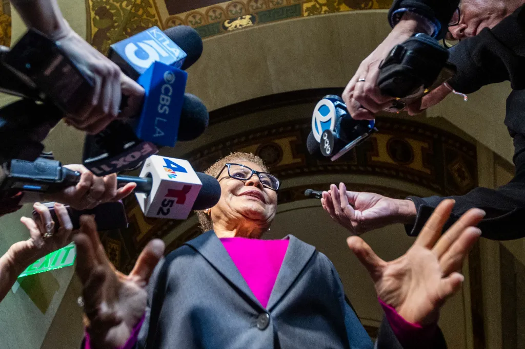 Los Angeles Mayor Karen Bass speaking to reporters, surrounded by microphones.