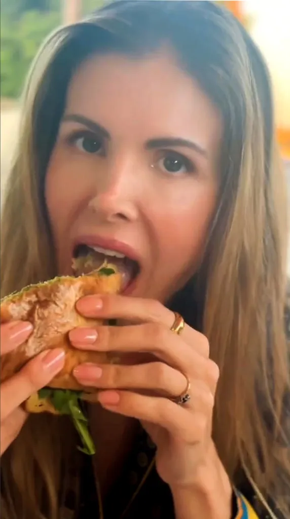 A woman with long blonde hair eats a sandwich.